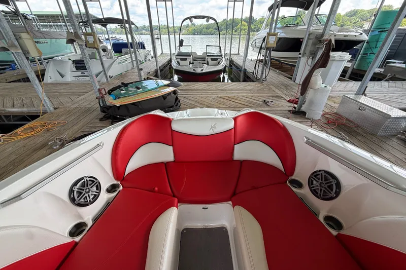 Slide: The Image of 2017 MasterCraft X23 boat with red and white seating, docked at a marina. - 26