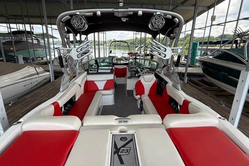 Slide: The Image of 2017 MasterCraft X23 boat with red and white seating, docked in a marina. - 18