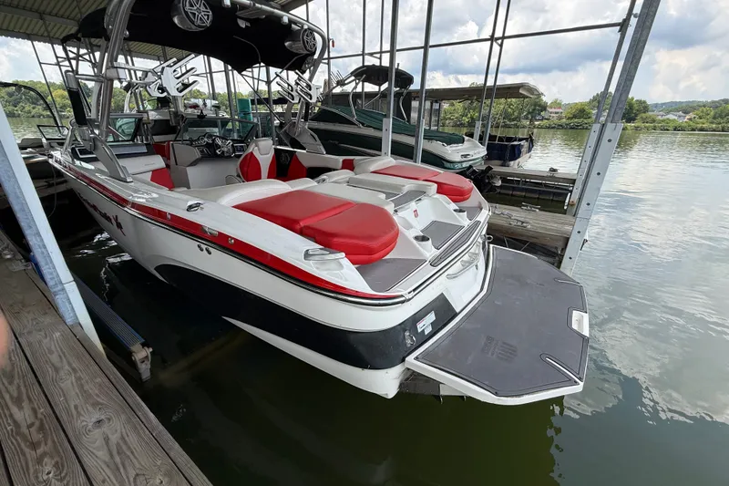 Slide: The Image of 2017 MasterCraft X23 boat with red and white seating, docked on a calm lake. - 14