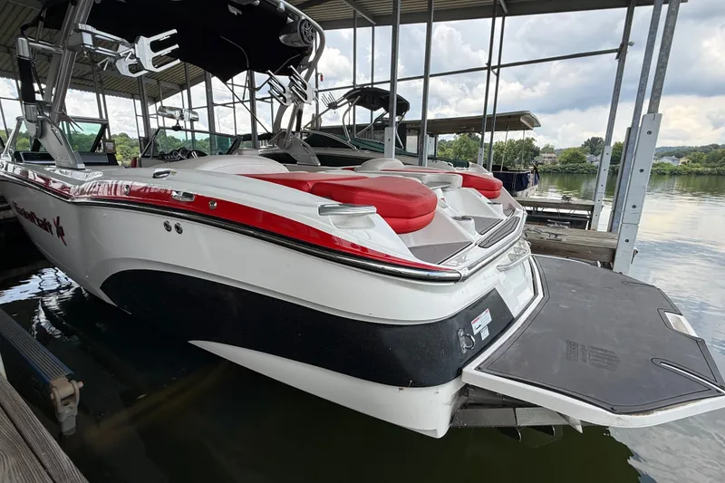 Slide: The Image of 2017 MasterCraft X23 boat docked, featuring red and white design under a covered marina. - 15