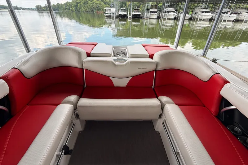 Slide: The Image of 2017 MasterCraft X23 boat interior with red and white seating, docked by a serene lake. - 33