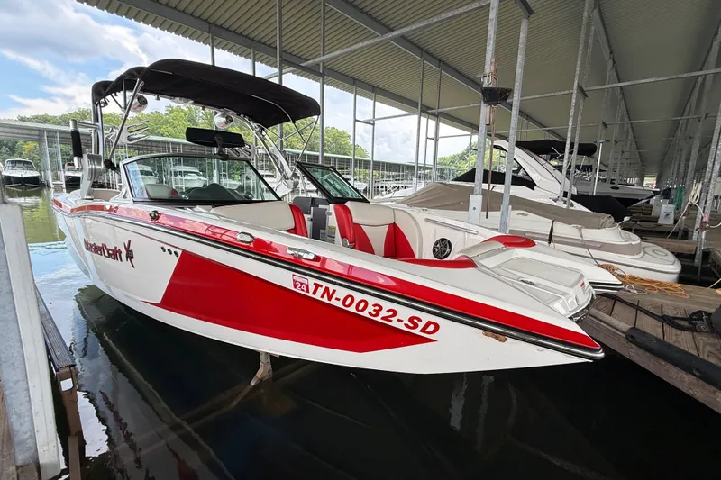 The Image of 2017 MasterCraft X23 boat docked in a marina, featuring red and white design. - 10