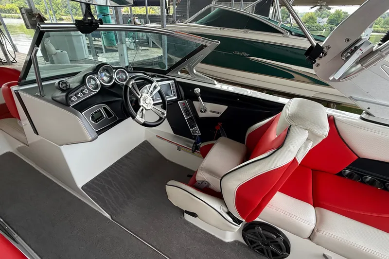 Slide: The Image of 2017 MasterCraft X23 boat interior with red and white seating, steering wheel, and dashboard controls. - 29