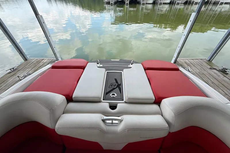 Slide: The Image of 2017 MasterCraft X23 boat interior with red and white seating, docked by calm water. - 37