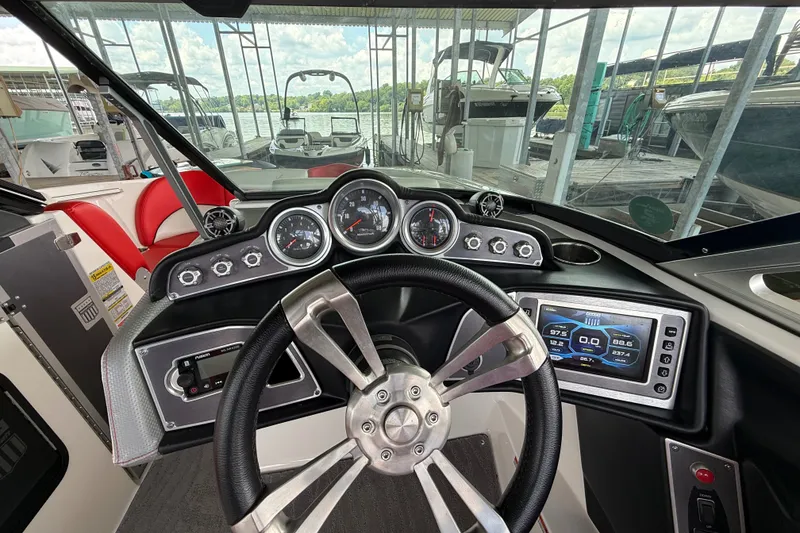 Slide: The Image of 2017 MasterCraft X23 boat dashboard with steering wheel and digital display in marina setting. - 31