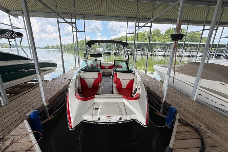 Slide: The Image of 2017 MasterCraft X23 boat docked, featuring red and white interior, under a covered marina. - 20