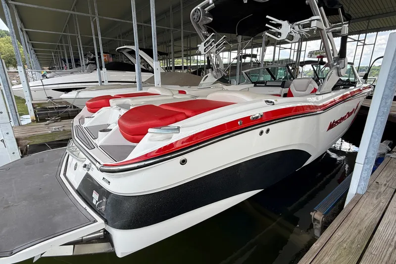 Slide: The Image of 2017 MasterCraft X23 boat with red and white seating, docked in a marina. - 13