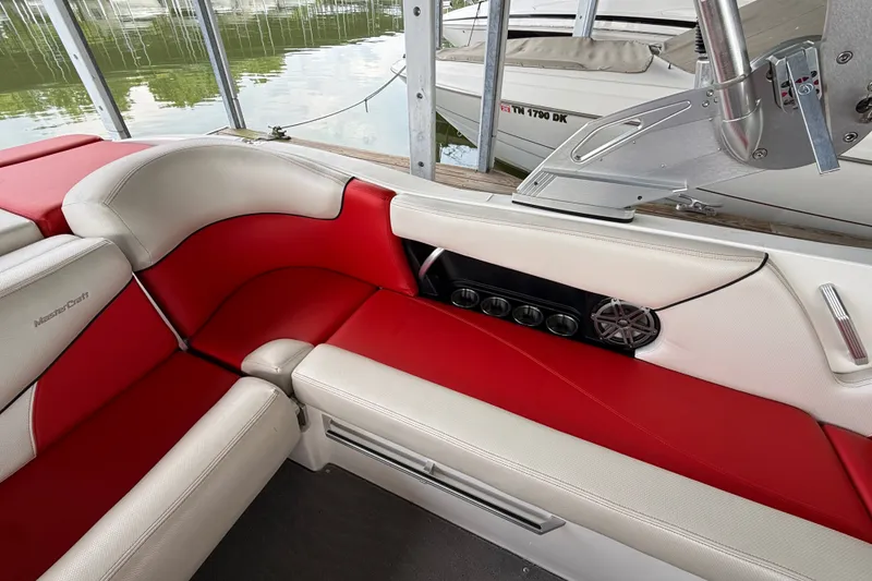 Slide: The Image of 2017 MasterCraft X23 boat interior with red and white seating, speaker, and cup holders. - 36