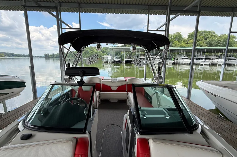 Slide: The Image of 2017 MasterCraft X23 boat docked, featuring sleek interior and canopy, surrounded by calm waters. - 21