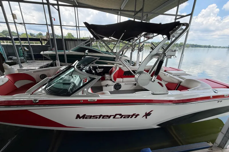 Slide: The Image of 2017 MasterCraft X23 boat docked, featuring red and white design with a black canopy. - 16