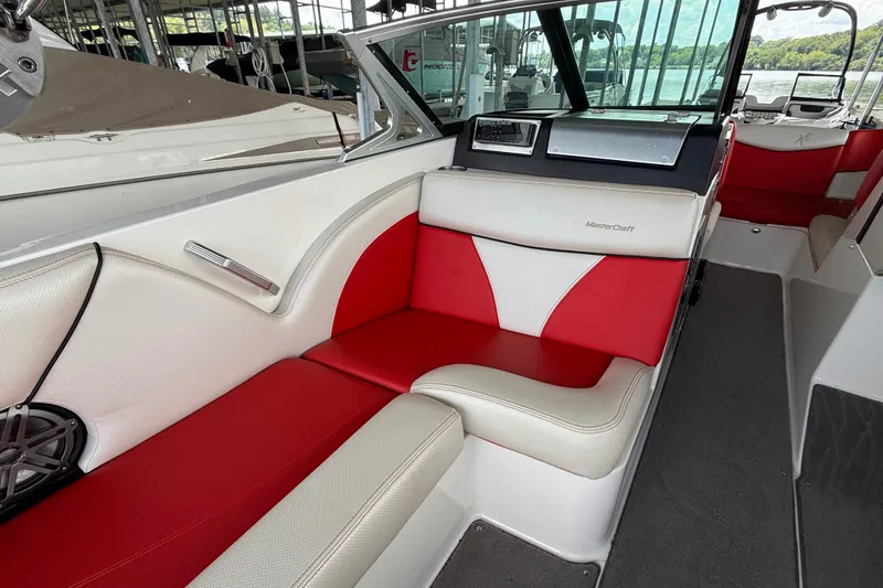 Slide: The Image of 2017 MasterCraft X23 boat interior with red and white seating, docked by the water. - 34