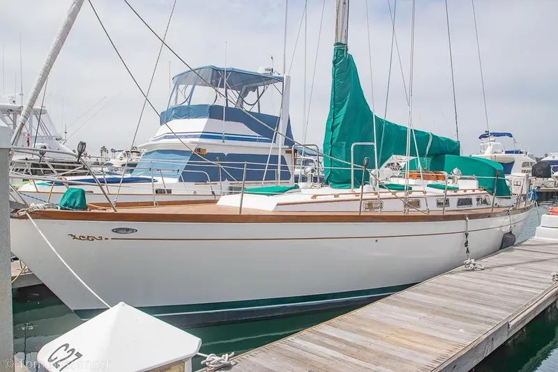 The Image of 1984 Cheoy Lee Pedrick 41 sailboat docked at marina with green covers. - 1
