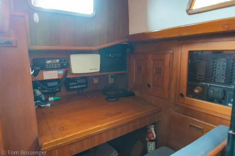 Slide: The Image of Navigation station inside 1984 Cheoy Lee Pedrick 41 sailboat, featuring wooden cabinetry and communication equipment. - 17