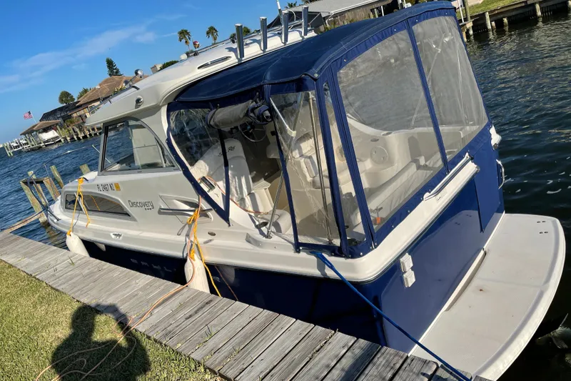 Slide: The Image of 2009 Bayliner Discovery 246 docked by a waterfront, featuring a blue and white exterior. - 20