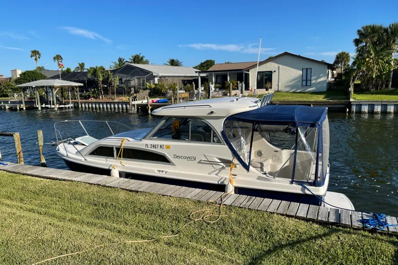 Slide: The Image of 2009 Bayliner Discovery 246 docked by waterfront homes under clear blue sky. - 18