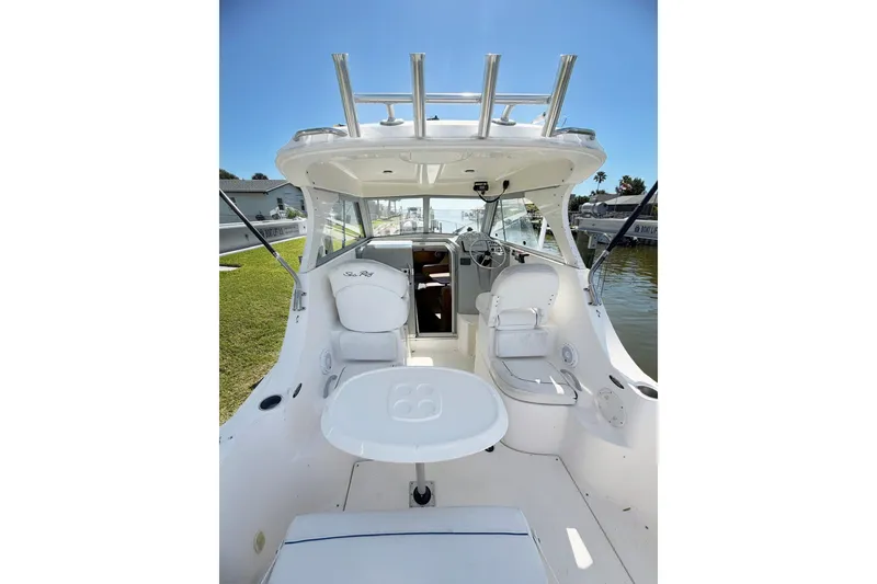 Slide: The Image of 2009 Bayliner Discovery 246 boat interior with seating and helm, docked by the water. - 14