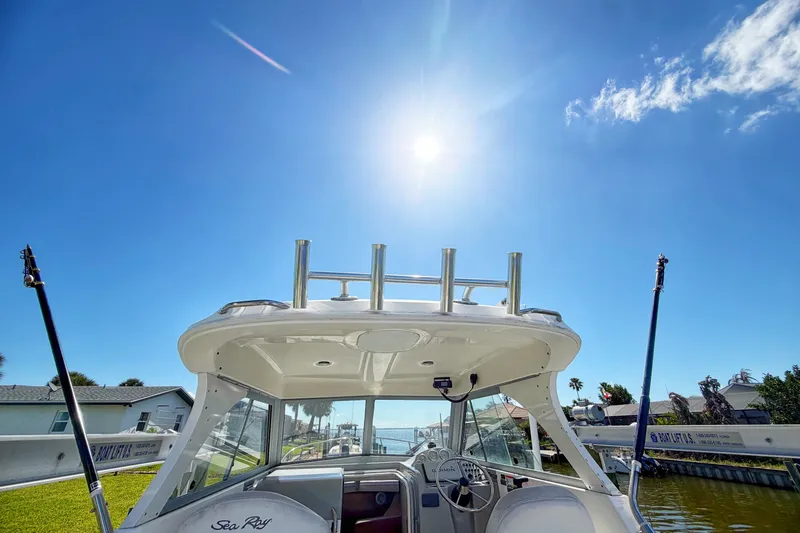 Slide: The Image of 2009 Bayliner Discovery 246 boat under bright sun, docked near a canal. - 13
