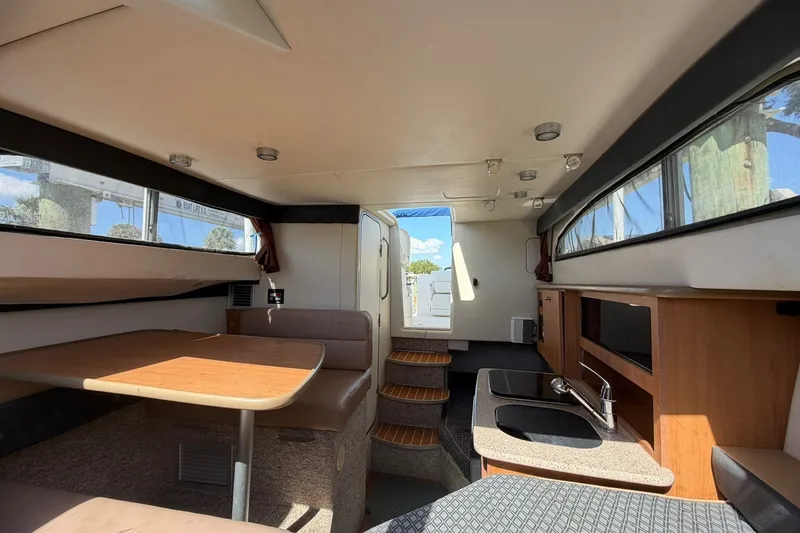 Slide: The Image of Interior of 2009 Bayliner Discovery 246 boat, featuring dining area and kitchenette. - 2
