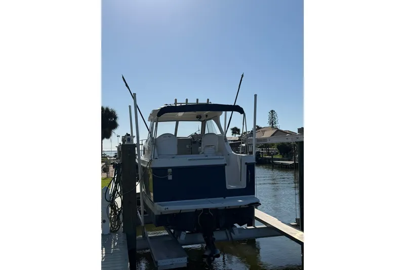 Slide: The Image of 2009 Bayliner Discovery 246 boat docked on a sunny day, rear view. - 16