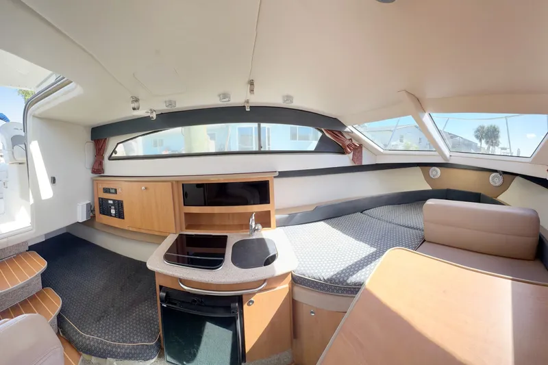 Slide: The Image of Interior of 2009 Bayliner Discovery 246 boat, featuring kitchenette and seating area. - 3