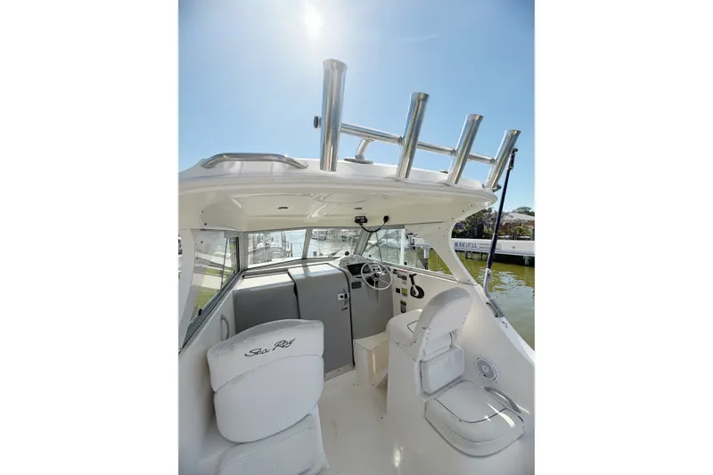 Slide: The Image of 2009 Bayliner Discovery 246 boat interior with helm, seating, and rod holders under clear sky. - 7