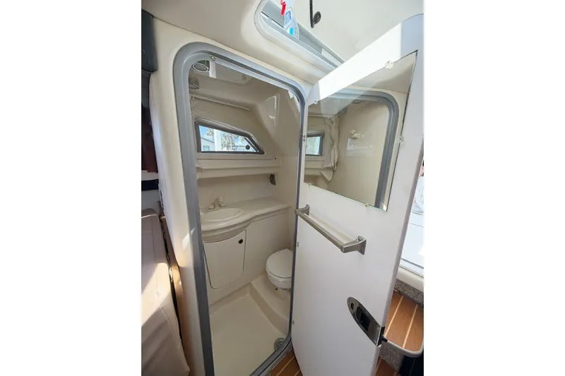 Slide: The Image of 2009 Bayliner Discovery 246 boat bathroom interior with sink, toilet, and window. - 5