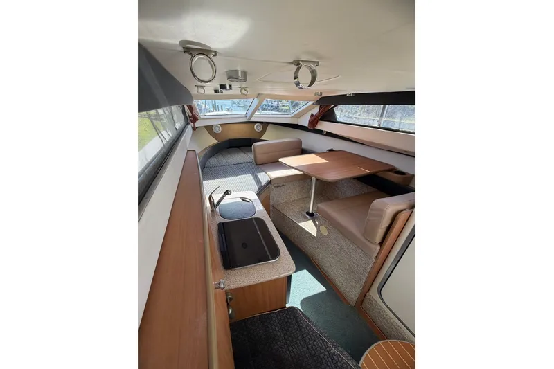 Slide: The Image of 2009 Bayliner Discovery 246 cabin interior with seating, table, and kitchenette. - 22