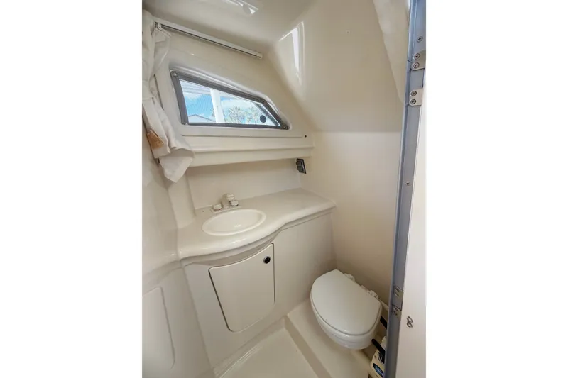 Slide: The Image of 2009 Bayliner Discovery 246 boat bathroom with sink, toilet, and window. - 6