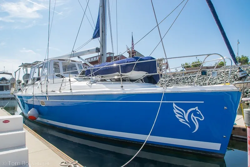 Slide: The Image of 2009 Hunter 50 Center Cockpit sailboat docked, featuring a striking blue hull with a winged horse logo. - 2