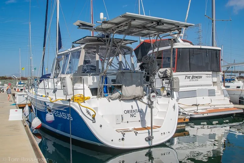 Slide: The Image of 2009 Hunter 50 Center Cockpit sailboat docked in a marina, featuring solar panels and nautical equipment. - 4