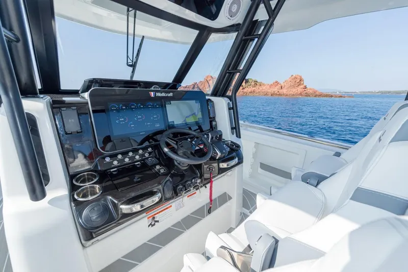 Slide: The Image of 2027 Wellcraft 38 T-Top boat cockpit with advanced navigation system, overlooking scenic ocean view. - 2