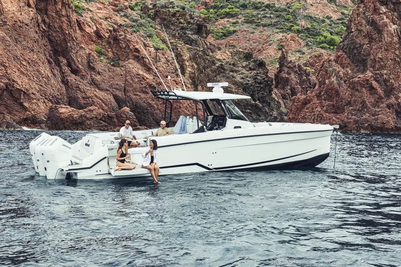 Slide: The Image of 2027 Wellcraft 38 T-Top boat with people, cruising near rocky coastline. - 10