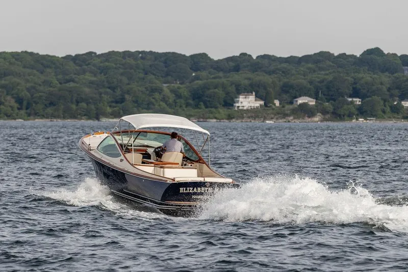 Slide: The Image of 2008 Hinckley Talaria 29R cruising on water with scenic shoreline background. - 33