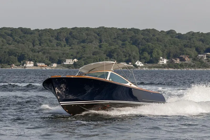 Slide: The Image of 2008 Hinckley Talaria 29R cruising on water with forested shoreline in background. - 5