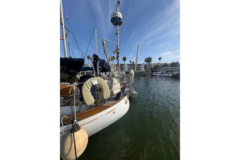 Slide: The Image of 1977 Tayana 37 Cutter sailboat docked in a sunny marina with clear skies. - 1