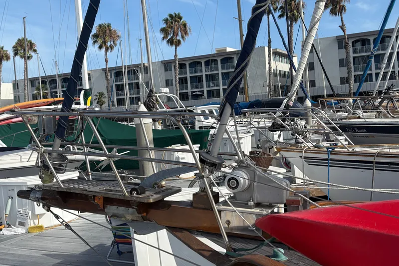 Slide: The Image of 1977 Tayana 37 Cutter sailboat docked at marina with palm trees and buildings. - 6
