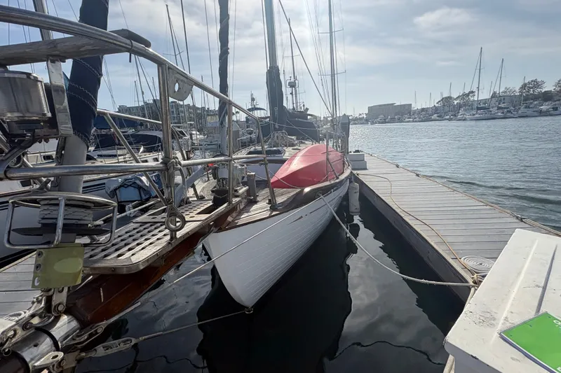 Slide: The Image of 1977 Tayana 37 Cutter sailboat docked at a marina under a cloudy sky. - 3