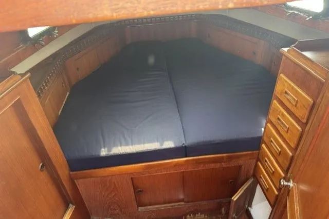 Slide: The Image of Interior cabin of 1977 Kelly Peterson 44 sailboat with wooden cabinetry and blue bedding. - 22