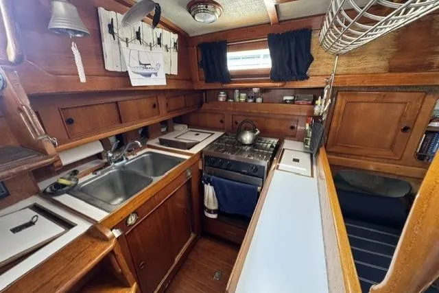 Slide: The Image of Cozy 1977 Kelly Peterson 44 yacht kitchen with wooden cabinetry and modern appliances. - 16