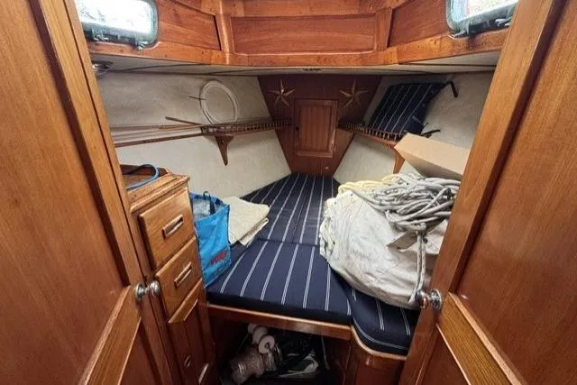 Slide: The Image of Cozy cabin interior of 1977 Kelly Peterson 44 sailboat with striped bedding and wooden cabinetry. - 14
