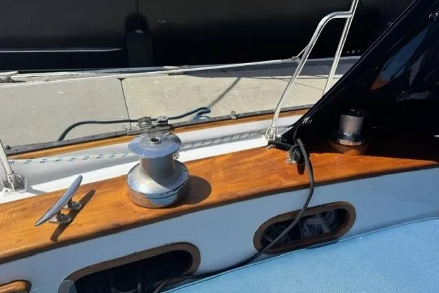 Slide: The Image of 1977 Kelly Peterson 44 sailboat deck with winch and cleat, featuring wooden trim. - 6