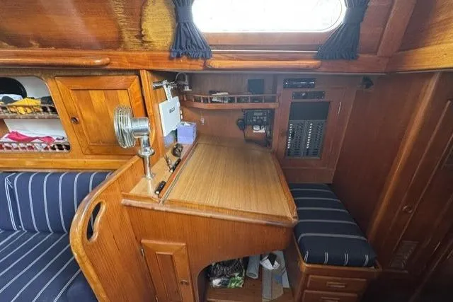 Slide: The Image of 1977 Kelly Peterson 44 yacht interior with wooden desk, striped cushions, and storage cabinets. - 17