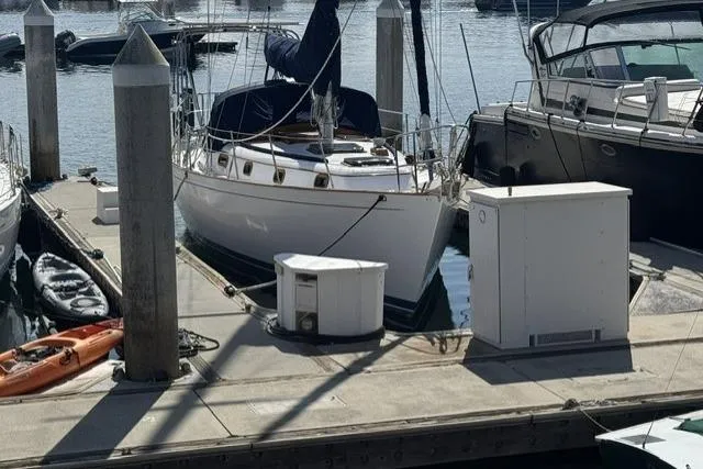Slide: The Image of 1977 Kelly Peterson 44 sailboat docked at marina, surrounded by other boats and equipment. - 2