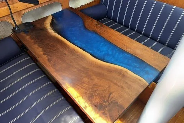 Slide: The Image of Wooden table with blue resin river design on a 1977 Kelly Peterson 44 sailboat. - 13