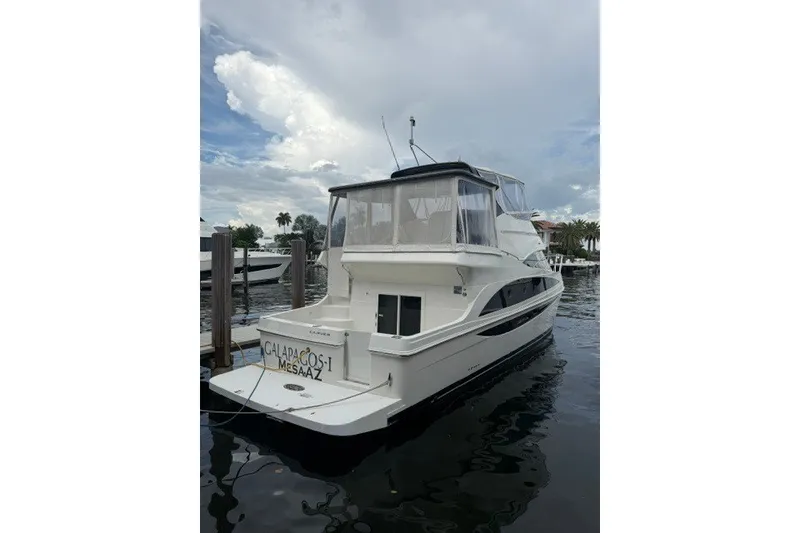 Slide: The Image of 2012 Carver 41 Cockpit Motor Yacht docked on a calm waterway under a cloudy sky. - 1