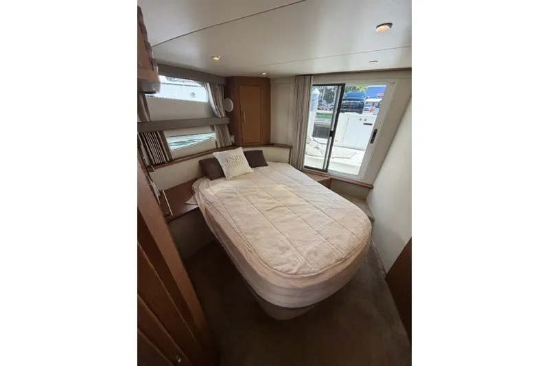 Slide: The Image of Cozy bedroom in 2012 Carver 41 Cockpit Motor Yacht with large windows and comfortable bedding. - 15
