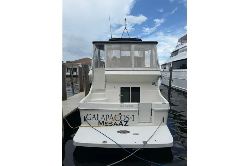 Slide: The Image of 2012 Carver 41 Cockpit Motor Yacht docked, rear view with "Galapagos-I" name visible. - 2