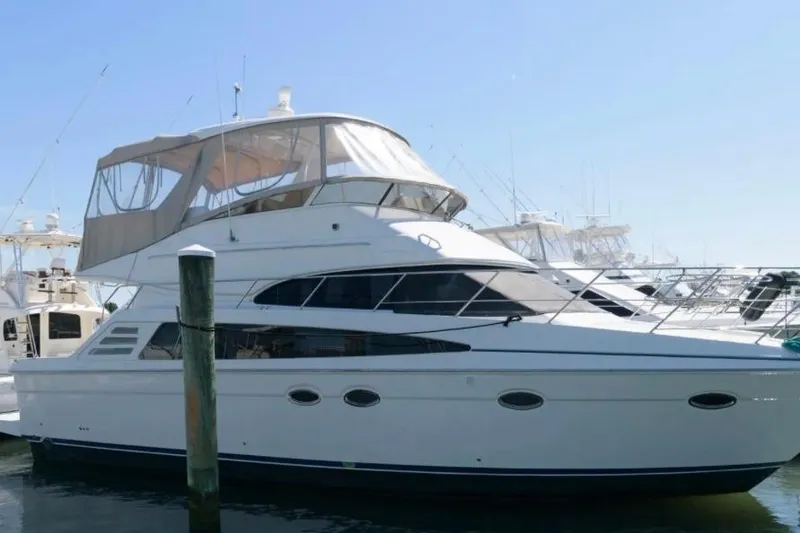 The Image of 2012 Carver 41 Cockpit Motor Yacht docked at marina under clear blue sky. - 0