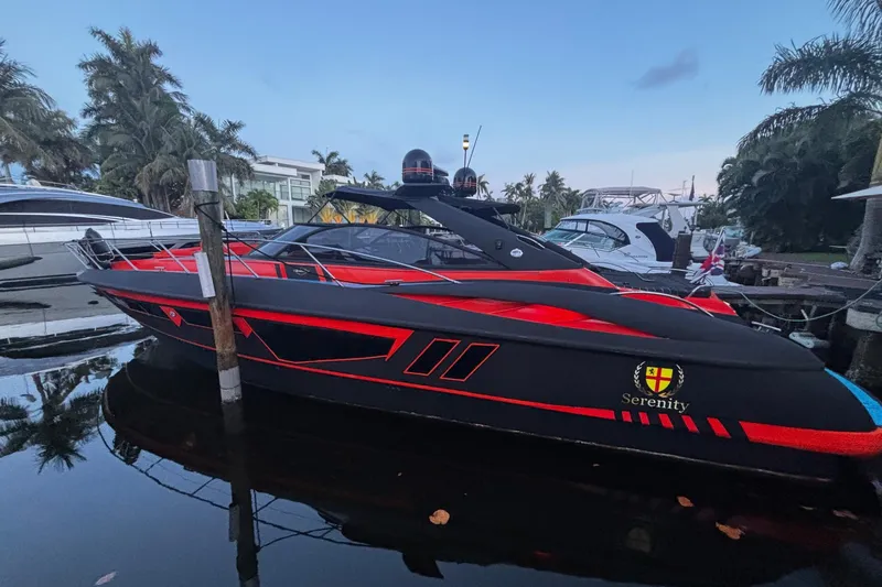 Slide: The Image of 2000 Sunseeker Camargue 50 yacht, black and red, docked near palm trees. - 2