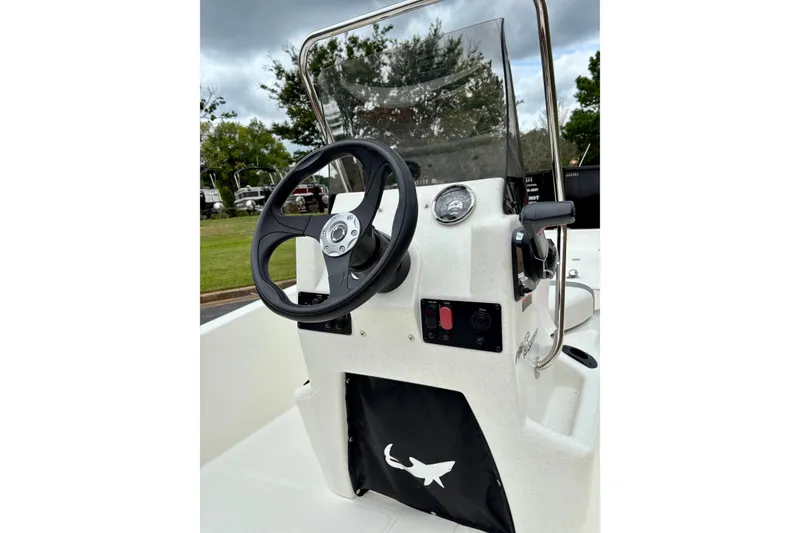 Slide: The Image of 2026 Mako Pro Skiff 15 CC console with steering wheel and controls, outdoors. - 2